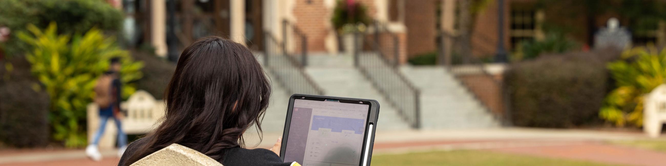 Female working on her tablet while sitting outside. 