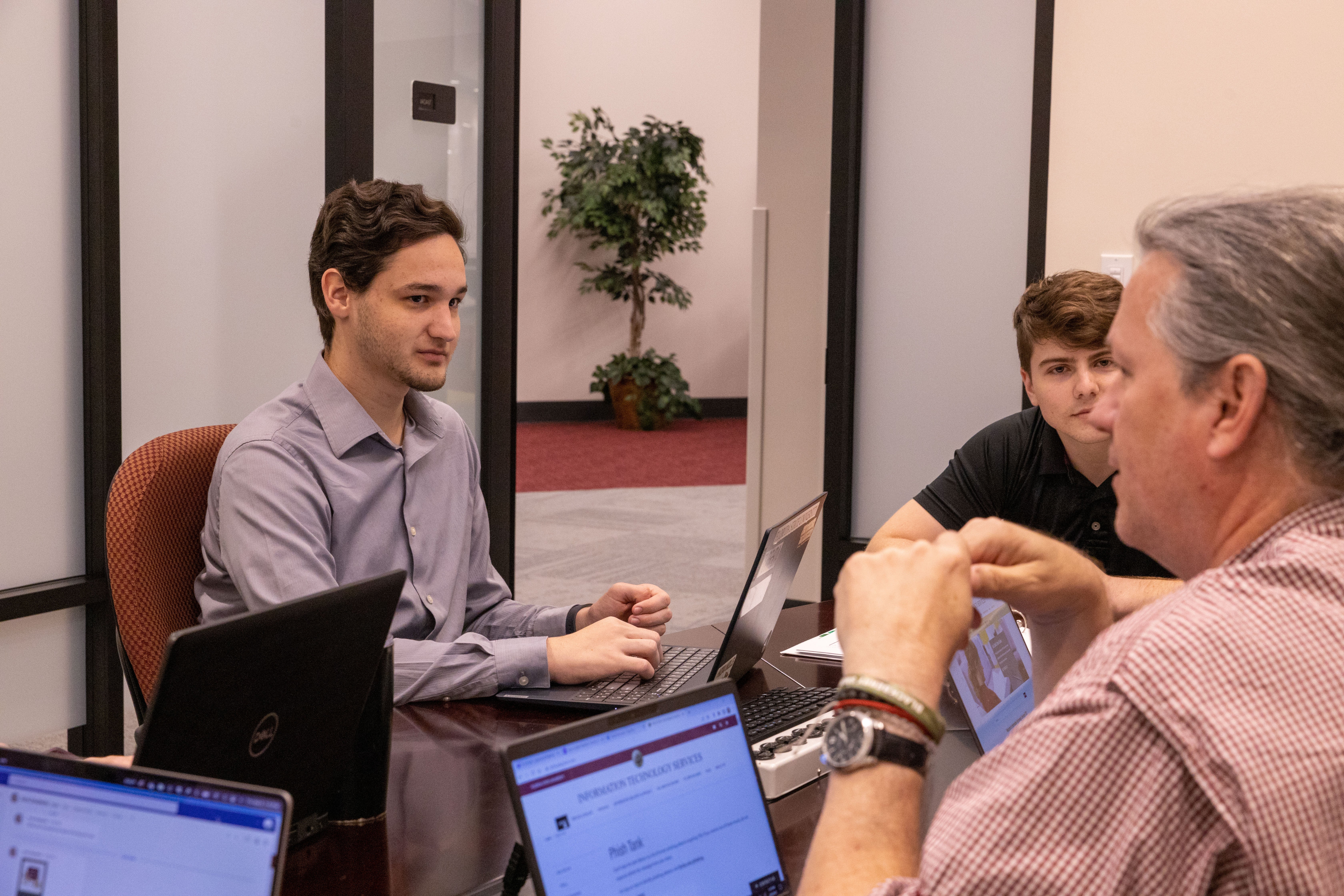 Three males with laptops talking